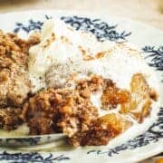 Whipped cream over caramel apple dump cake on a plate.