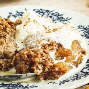 Whipped cream over caramel apple dump cake on a plate.