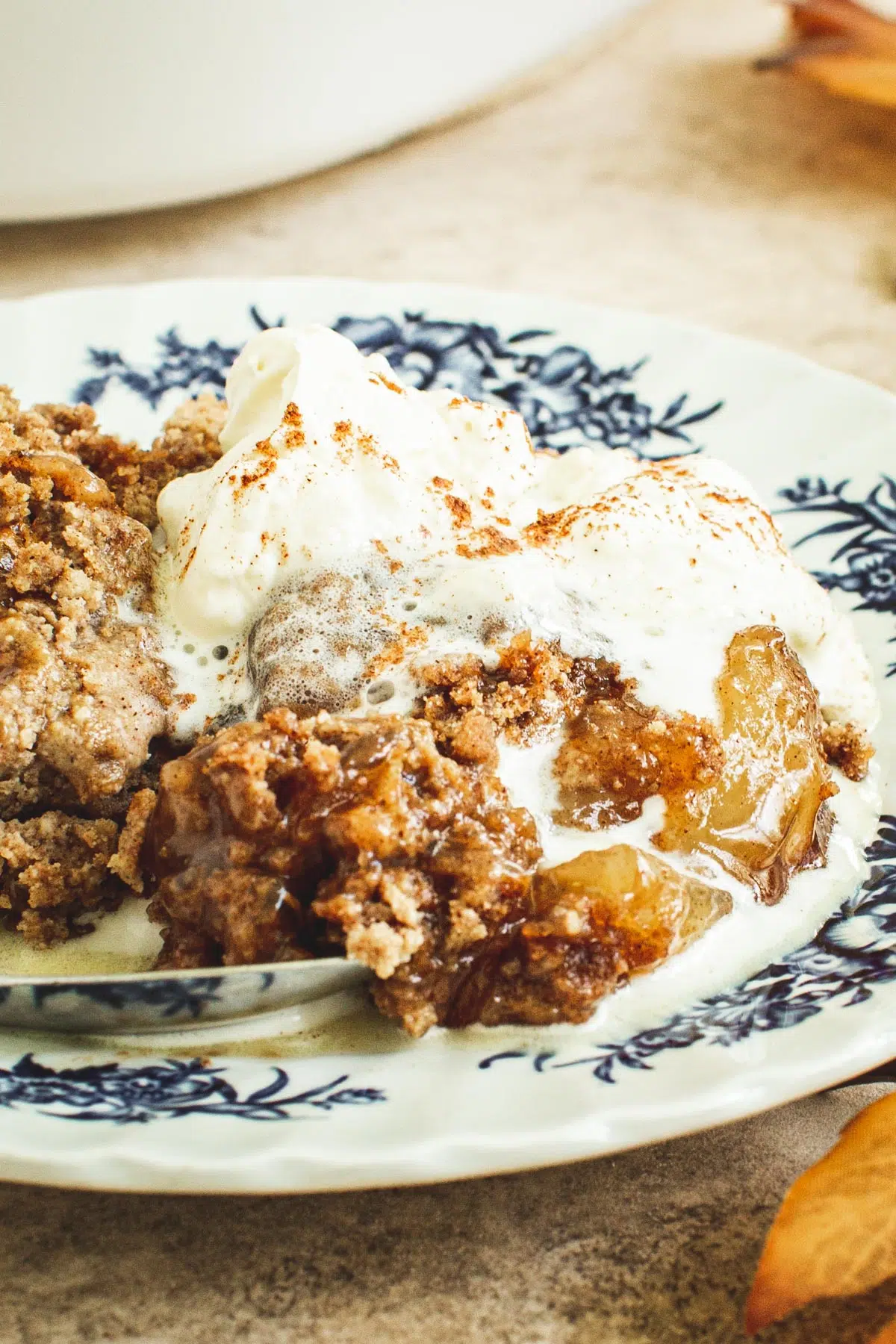 Whipped cream over caramel apple dump cake on a plate.