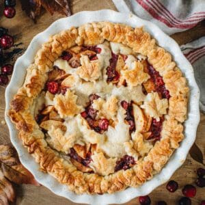 Apple cranberry pie in a white pie dish.