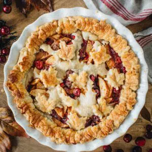 Apple cranberry pie in a white pie dish.