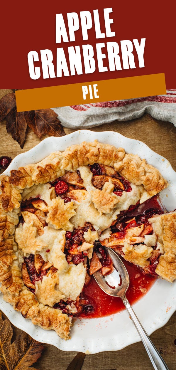 Apple cranberry pie with a slice cut out and a silver serving spoon.