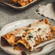 Butternut squash enchiladas on a plate with a fork.