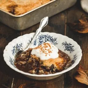 Pecan cobbler in a dessert bowl with blue flowers and a silver spoon.