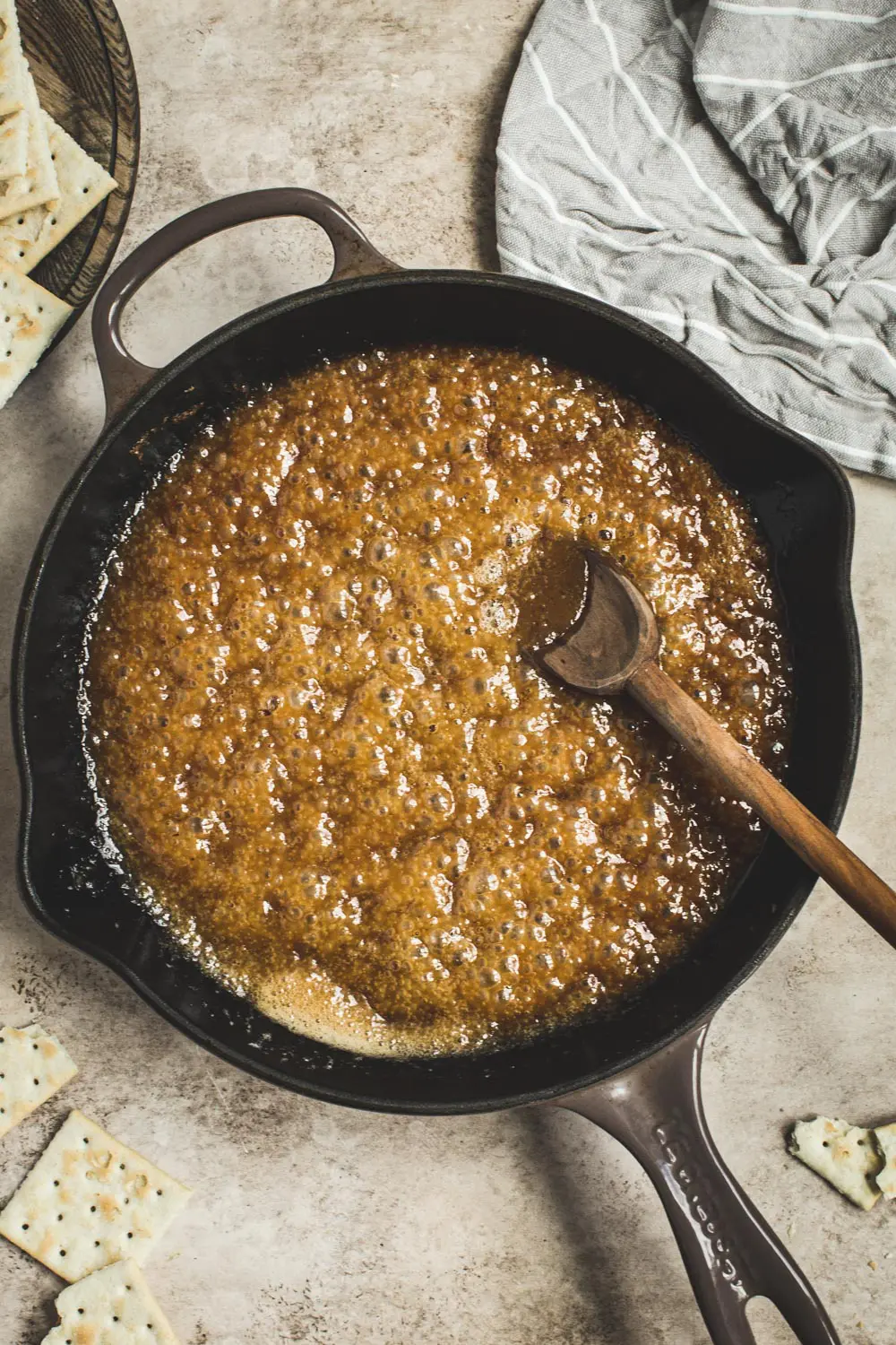 Butter and brown sugar mixture in an iron skillet with a wooden spoon.
