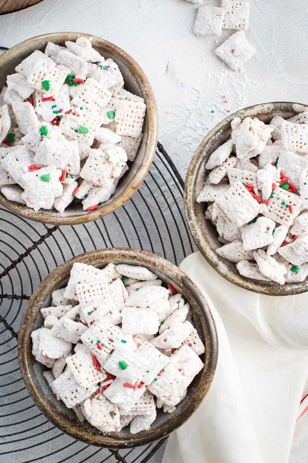 Three bowls of peppermint puppy chow sitting on a wire rack.
