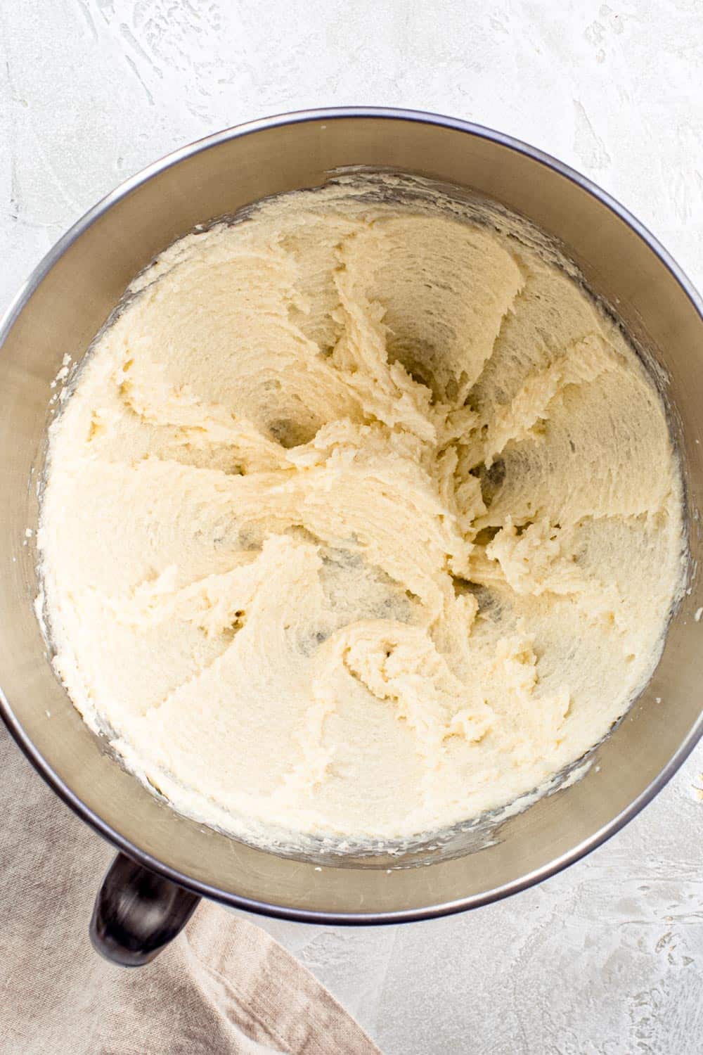 Butter and sugar cookie dough mixture in mixing bowl.