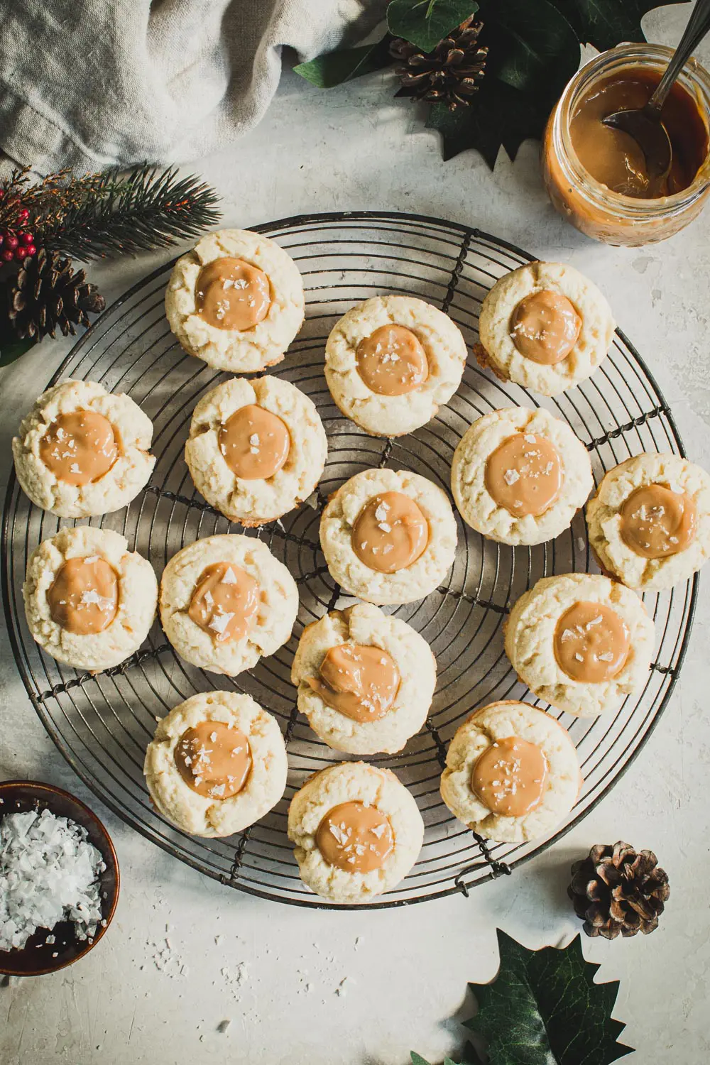 Dulce de leche thumbprint cookies on a round wire rack.