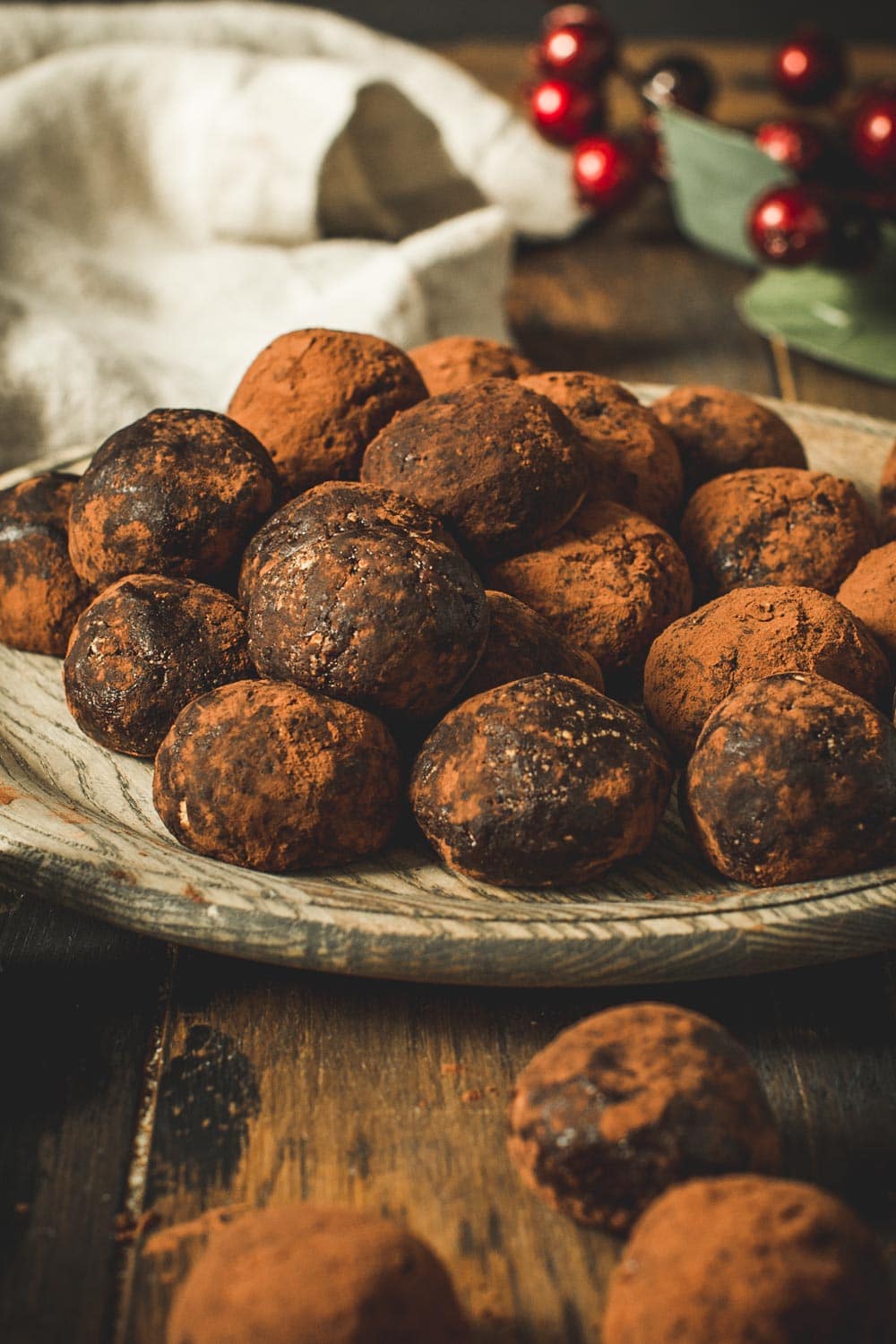 Chocolate rum balls stacked on a wooden plate.