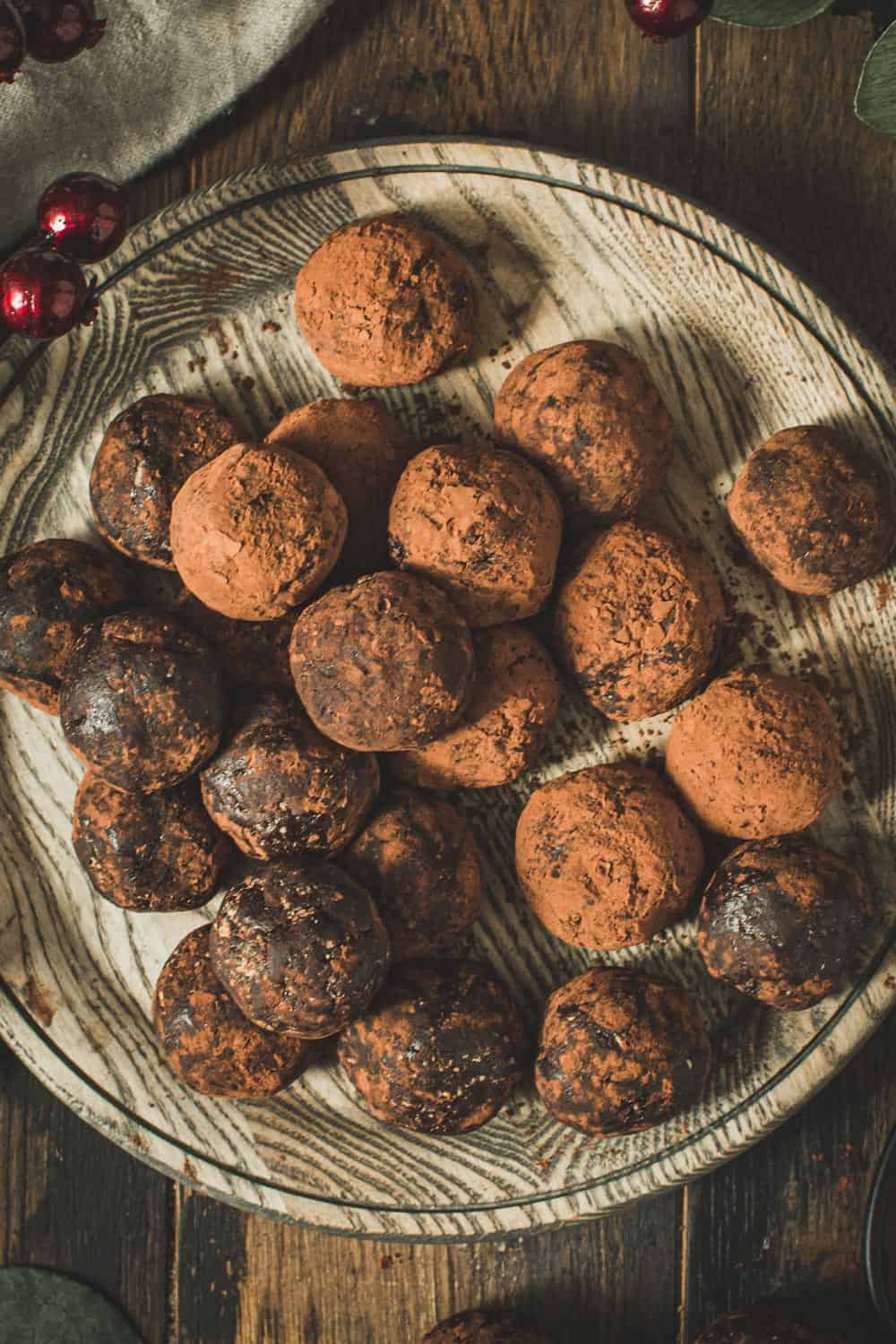 Rum balls coated in cocoa powder on a wooden plate.