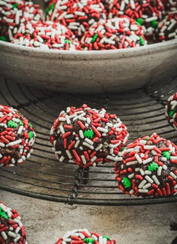Old fashioned rum balls coated in Christmas sprinkles on a wire rack.
