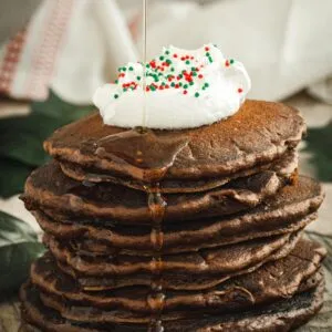 Whipped cream and sprinkles on top of stacked pancakes.