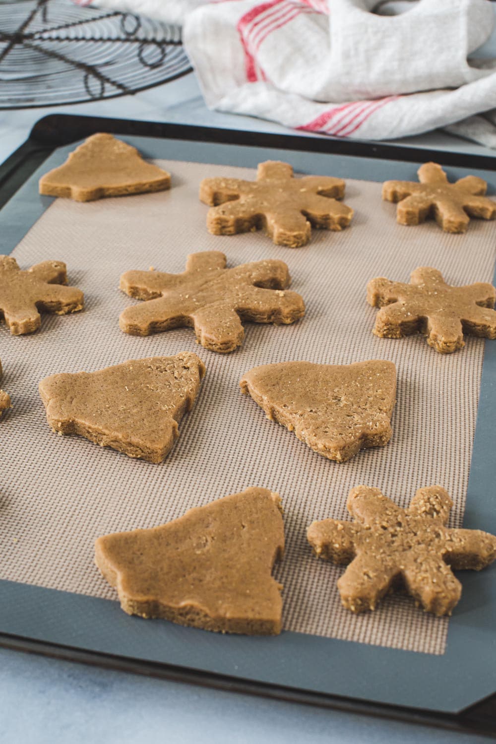 Gingerbread cookie dough cutouts on a baking sheet.
