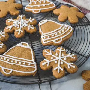 Gingerbread cookies covered with icing on a round wire rack.