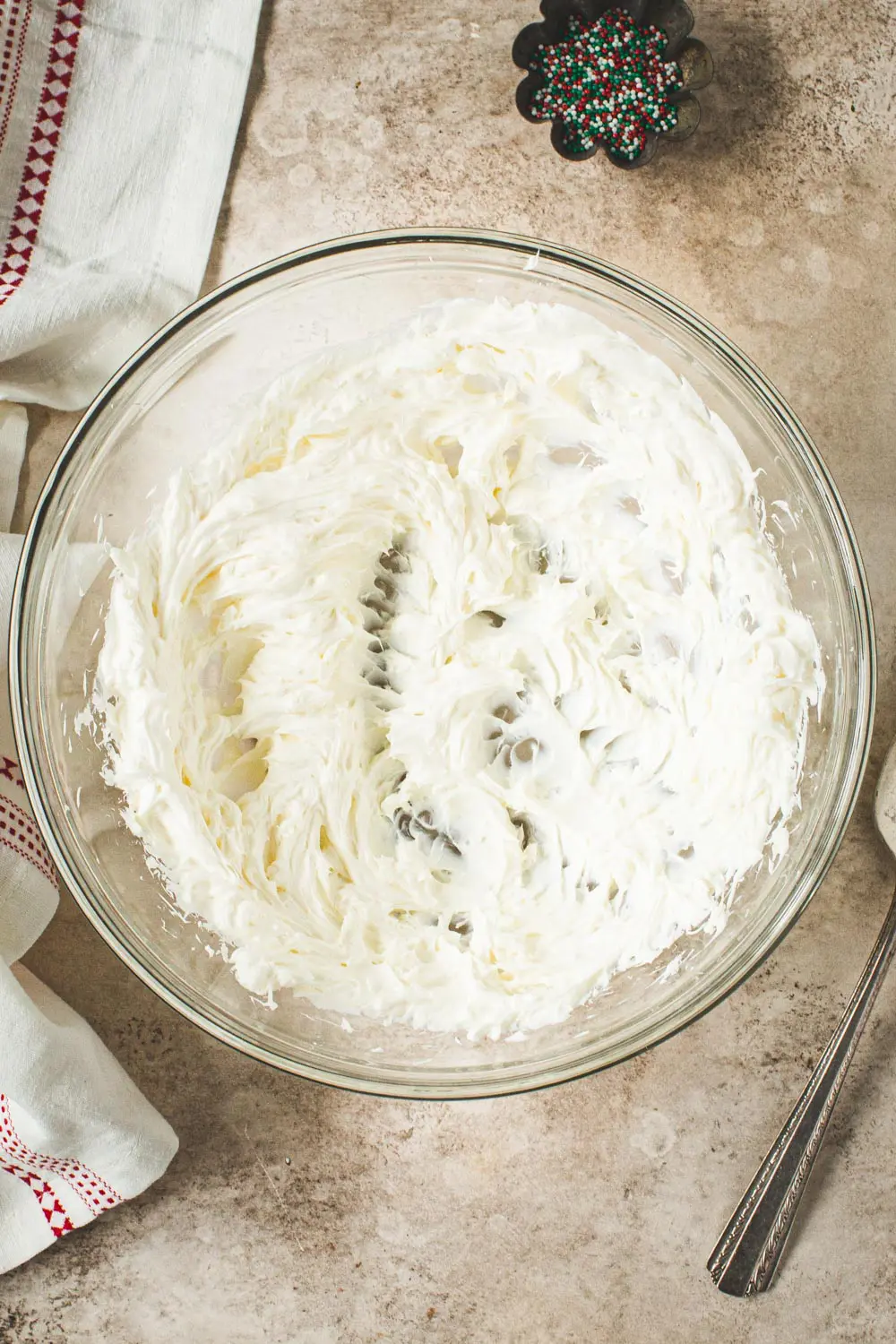 Beaten cheesecake in glass mixing bowl.