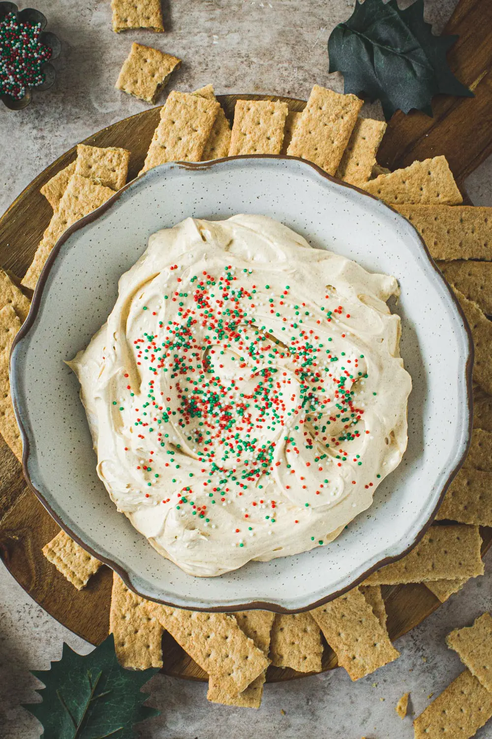 Gingerbread cheesecake dip in a bowl with graham crackers surrounding it on a cutting board.