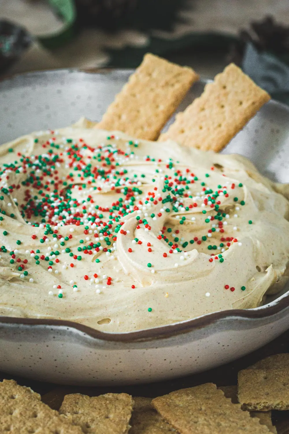 Gingerbread cheesecake dip topped with sprinkle and graham crackers inside.