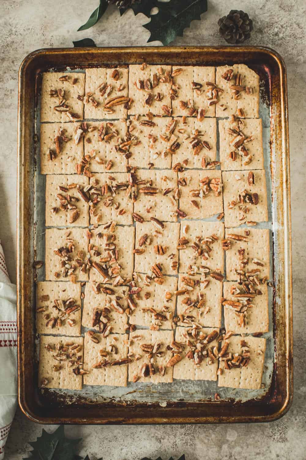 Graham Crackers covered in pecans on a rimmed baking sheet.