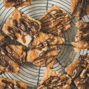 Praline bars drizzled in chocolate on a wire rack.