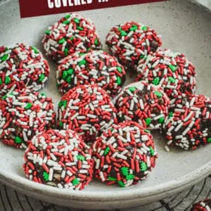 Old fashioned rum balls covered in Christmas sprinkles in a white bowl and on top of a wire rack.