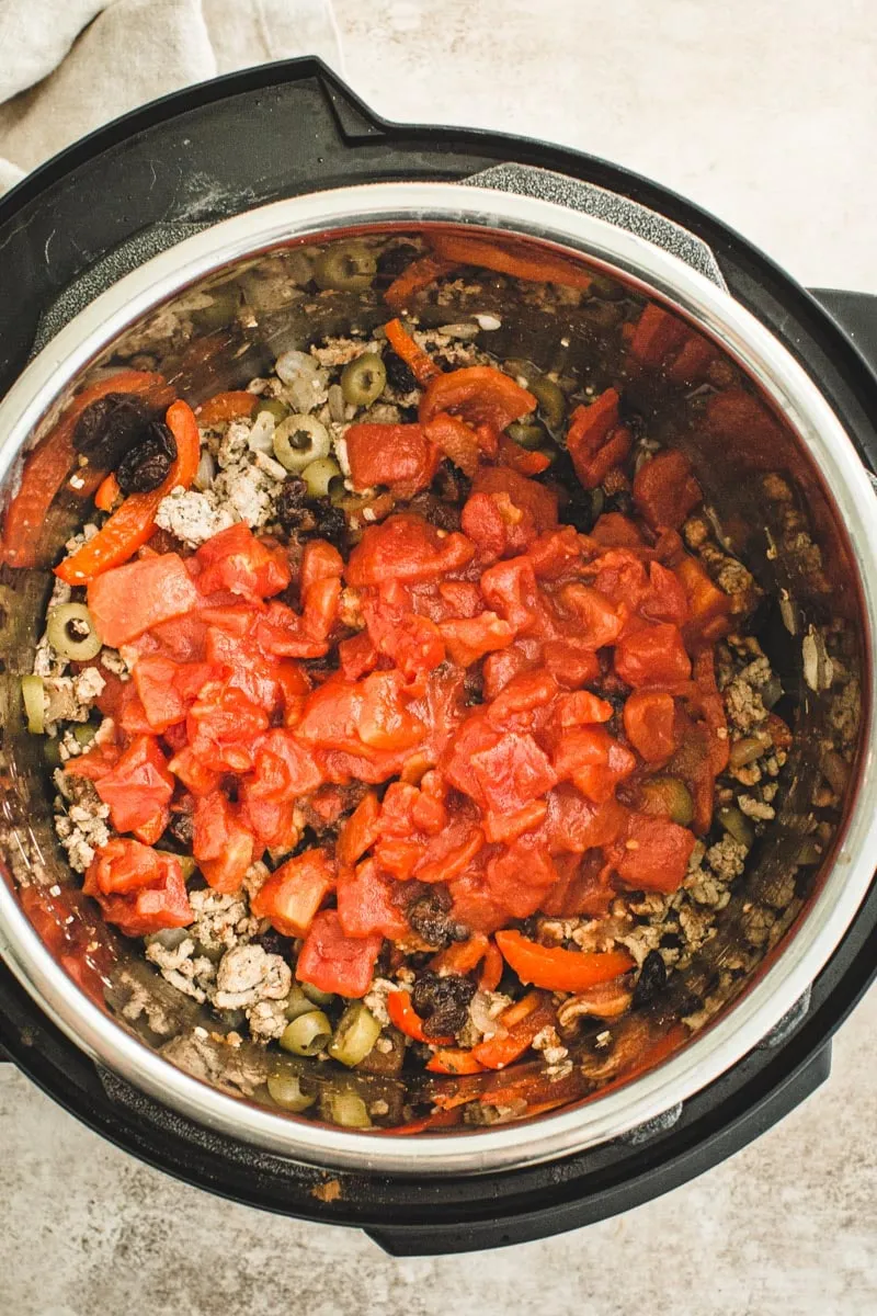 Picadillo ingredients layered in the Instant Pot.