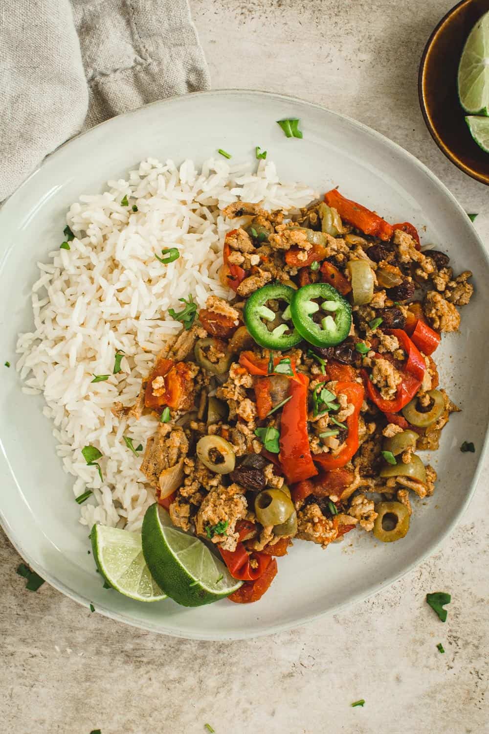 Instant pot picadillo topped with cilantro and lime wedges over rice.