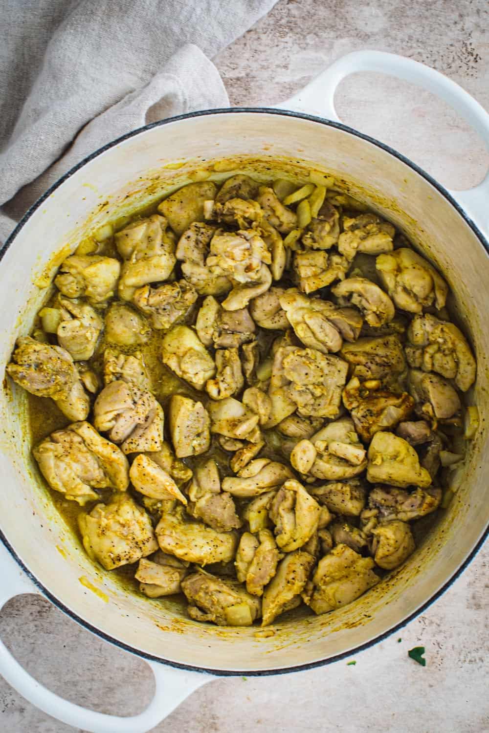 Cooked chicken in white Dutch Oven.