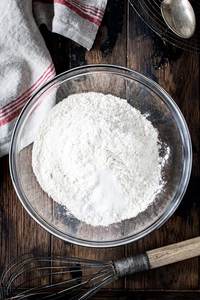 Bundt cake dry ingredients in glass mixing bowl with wire whisk beside.