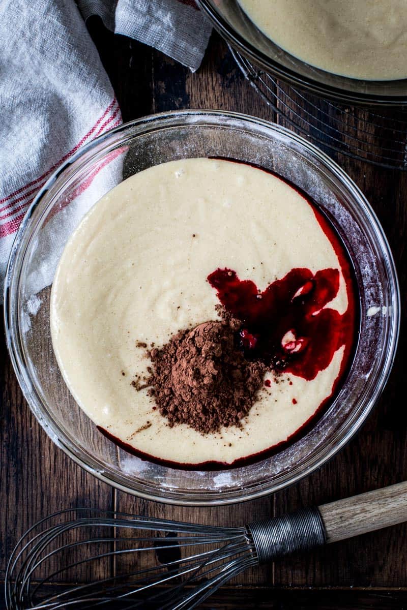 Red velvet bundt cake batter in mixing bowl with wire whisk next to it.