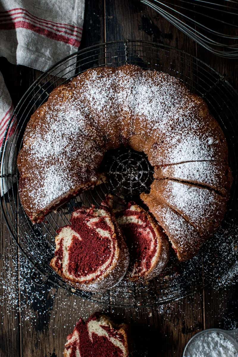 Red velvet marble bundt cake with powdered sugar on top and slices cut out.