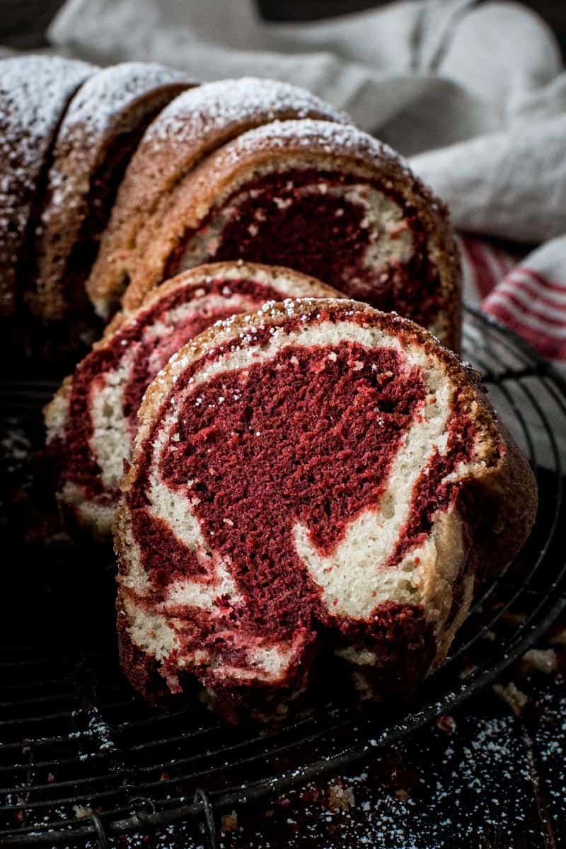 Slices of red velvet marble bundt cake leaning against each other on a round wire rack.