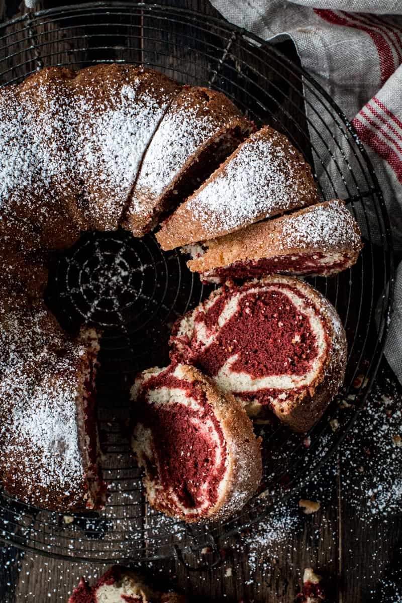 Red velvet marble bundt cake sliced and covered in powdered sugar.