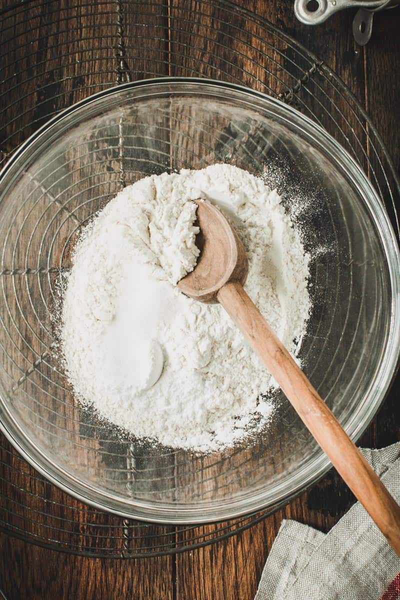 Flour mixture for skillet brownies in a glass mixing bowl with a wooden spoon.