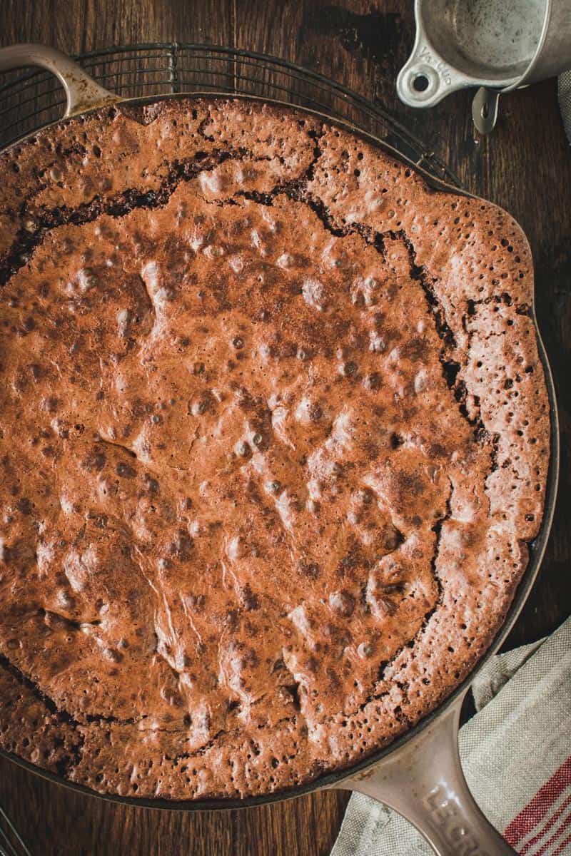Skillet brownie in a brown cast iron skillet on a wire rack.