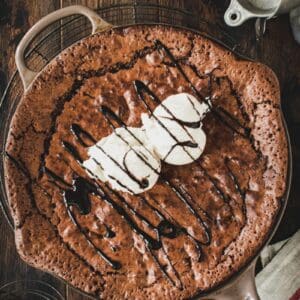 Skillet brownie topped with vanilla ice cream and chocolate sauce.