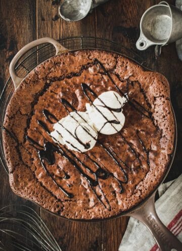 Skillet brownie topped with vanilla ice cream and chocolate sauce.