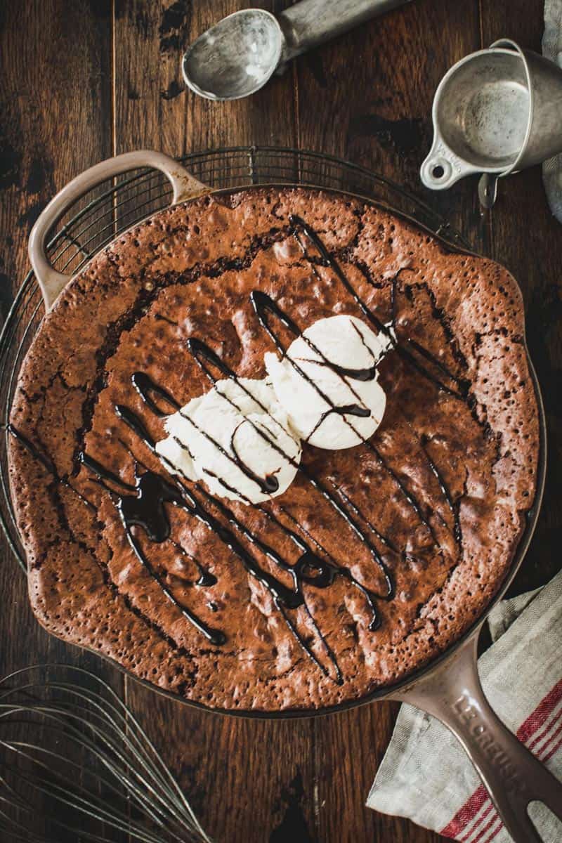 Skillet brownie topped with vanilla ice cream and chocolate sauce.