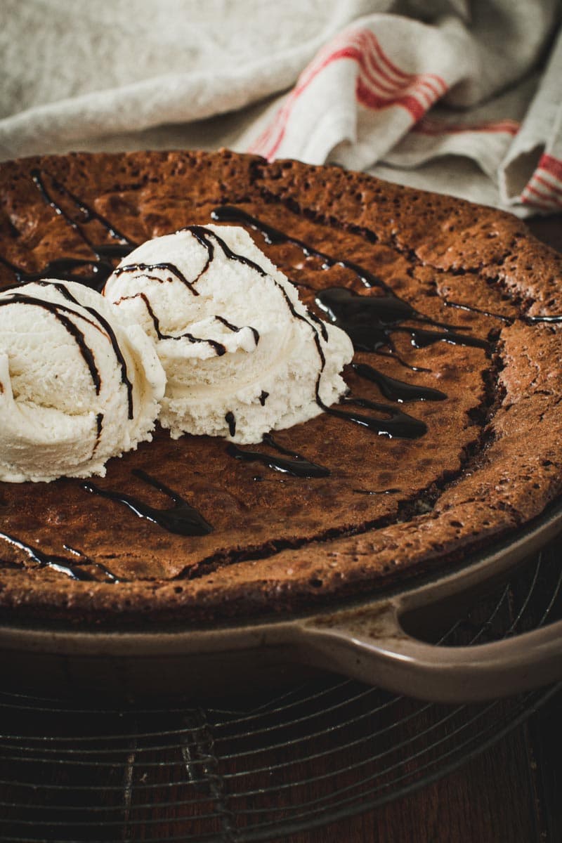 Side view of skillet brownies topped with vanilla ice cream and chocolate syrup.