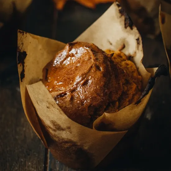 Gluten free pumpkin spice muffin in a brown muffin wrapper.