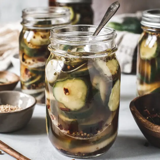 Mason jar full of refrigerator pickles with a small serving spoon inside.