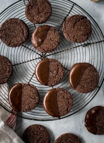 Chocolate-dipped soft ginger cookies sitting on a round wire rack.