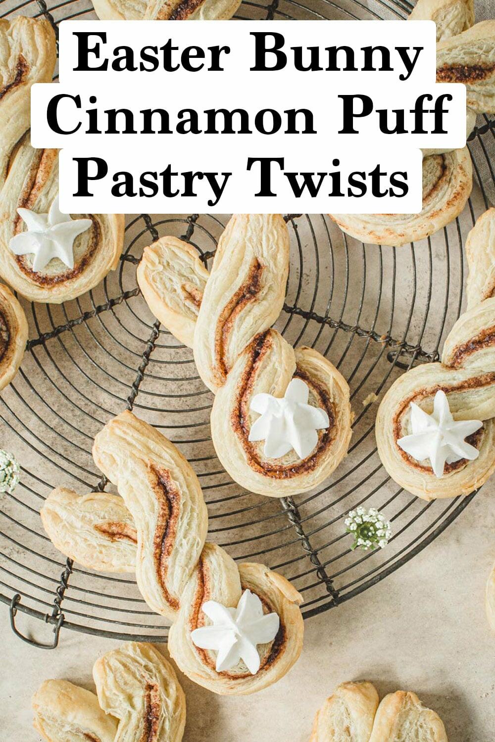 Cinnamon puff pastries shaped like bunnies with frosting tails on a wire rack.