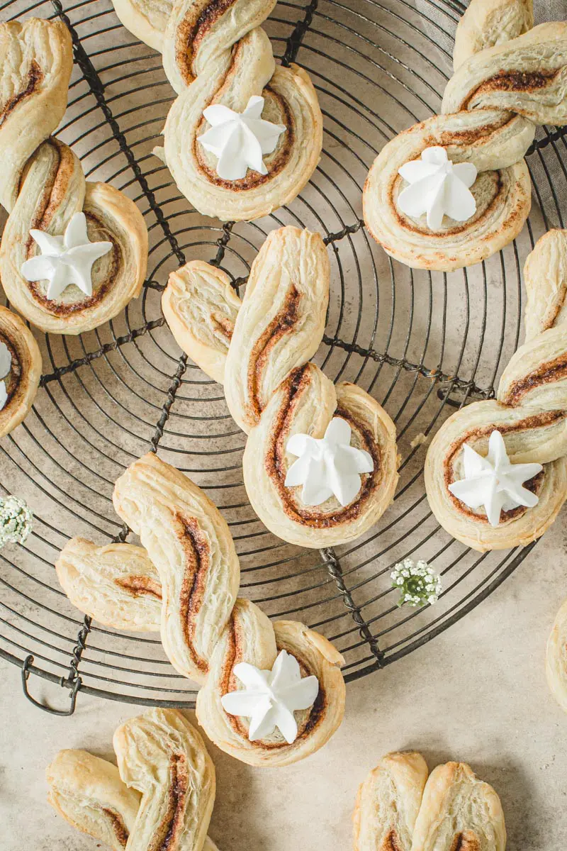 Easter bunny cinnamon puff pastry twists with frosting tails on a wire rack.