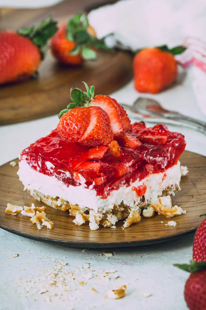 Gluten-free strawberry pretzel salad topped with a sliced strawberry.