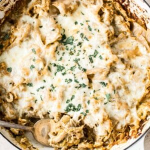 Silver serving spoon in chicken enchilada skillet topped with fresh cilantro.