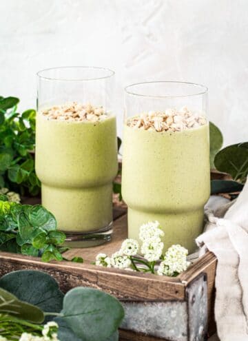 Two easy green smoothies in tall glasses topped with granola.