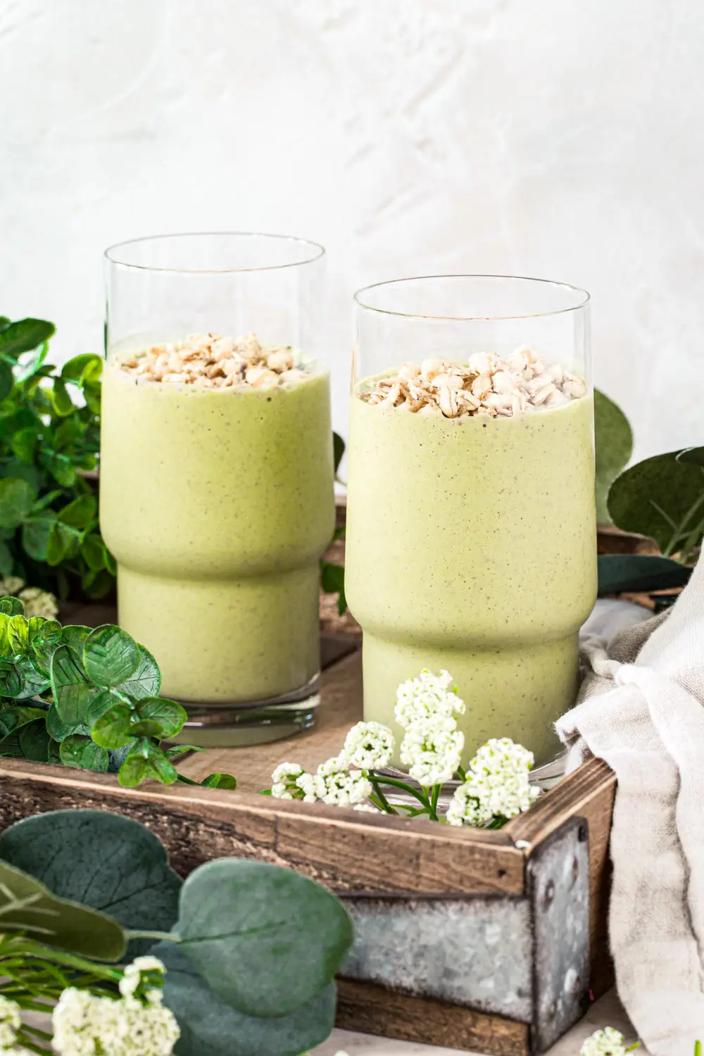 Two easy green smoothies in tall glasses topped with granola.