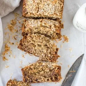 Slices cut off vegan banana bread with a wooden handled knife laying next to it.