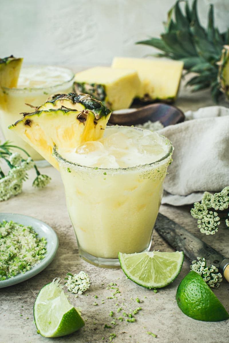 Pineapple coconut margarita with a sugared rim and pineapple wedge on the glass.