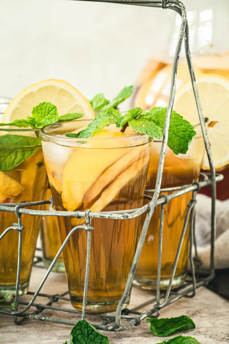 Glasses of sangria iced tea topped with mint in a metal drink carrier.